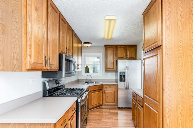 a kitchen with stainless steel appliances granite countertop a refrigerator a stove and a sink with wooden floor