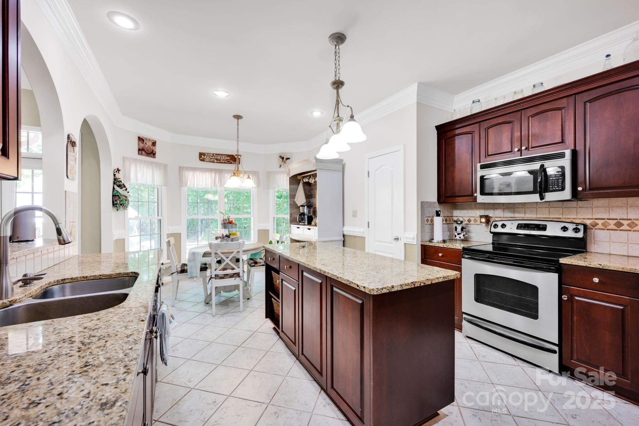 3610 Providence Mill Road Maiden, NC 28650 - Photo 6 of 44 a kitchen with stainless steel appliances granite countertop a stove top oven a sink dishwasher a dining table and chairs with wooden floor