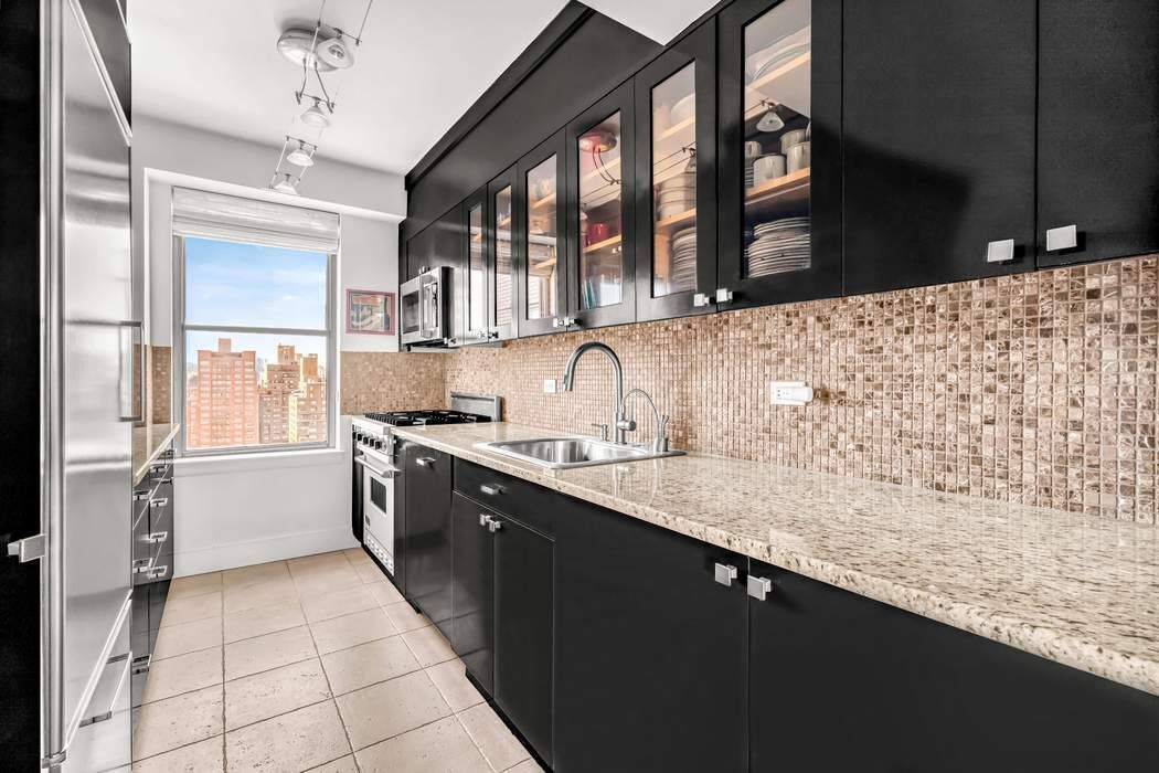 169 East 69th Street, Unit 19A Manhattan, NY 10021 - Photo 4 of 13 a large kitchen with granite countertop a sink and a stove