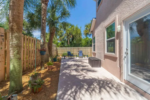 a view of a patio with table and chairs potted plants and palm tree