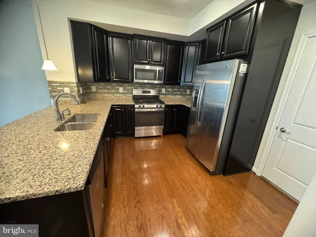 a kitchen with granite countertop a refrigerator a stove a sink and dishwasher