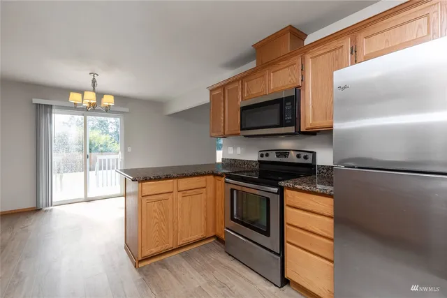 a kitchen with granite countertop a refrigerator stove and microwave