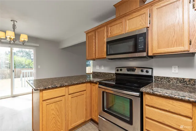a kitchen with granite countertop cabinets stainless steel appliances and a window