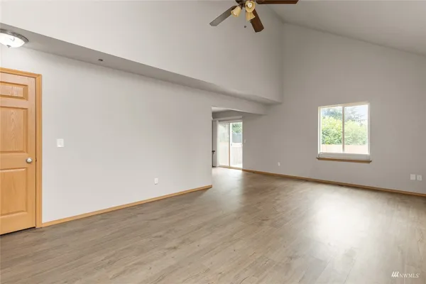 an empty room with wooden floor cabinet and windows