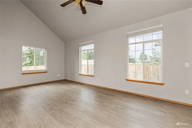 a view of an empty room with a window and wooden floor
