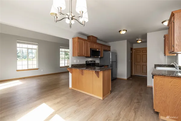 a kitchen with stainless steel appliances granite countertop a refrigerator a stove top oven a sink and dishwasher with wooden floor