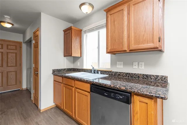 a kitchen with granite countertop a sink stove and cabinets