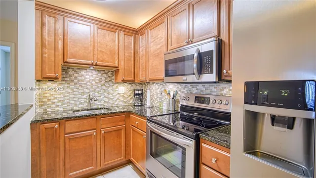 a kitchen with stainless steel appliances granite countertop a stove a sink and a microwave