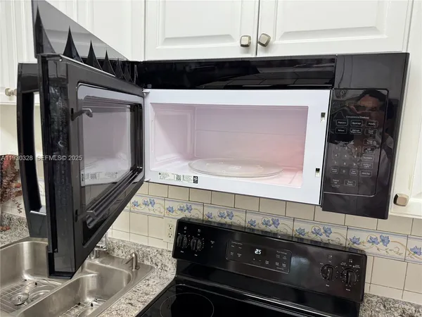 an empty room with kitchen and chandelier fan