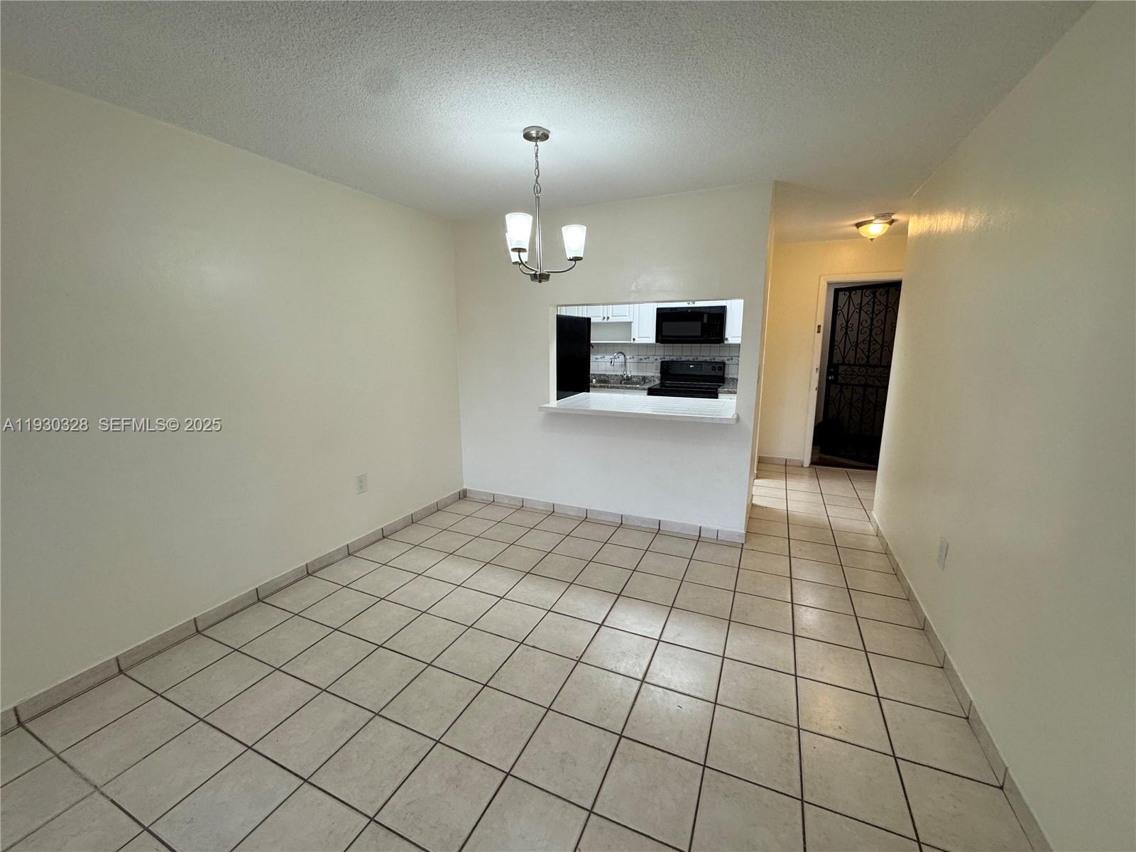 677 Southwest 9th Avenue, Unit 212 Miami, FL 33130 - Photo 9 of 19 an empty room with kitchen and chandelier fan