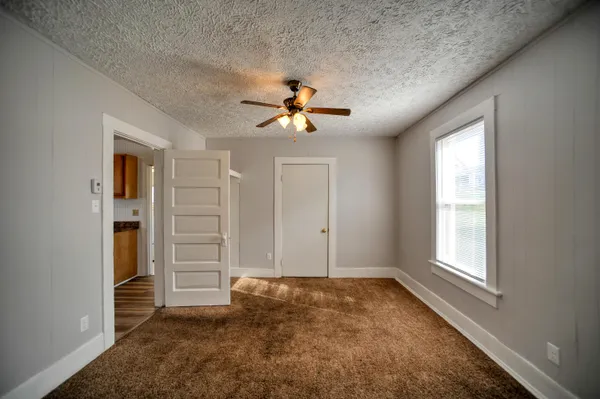 an empty room with closet and a ceiling fan