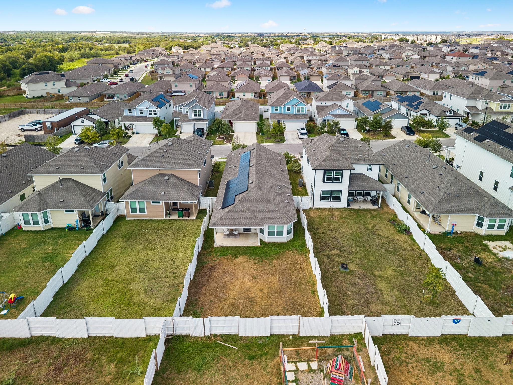 164 Appleberry Lane Elgin, TX 78621 - Photo 31 of 40 An aerial view showcases the fenced backyard and solar panels of this suburban neighborhood home.