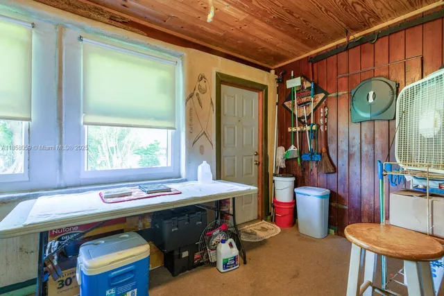 a utility room with stainless steel appliances lots of clutter and furniture