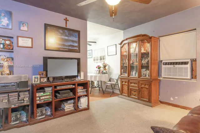 a living room with furniture a flat screen tv and kitchen view