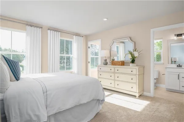 a bedroom with a bed a mirror on dresser and a large window
