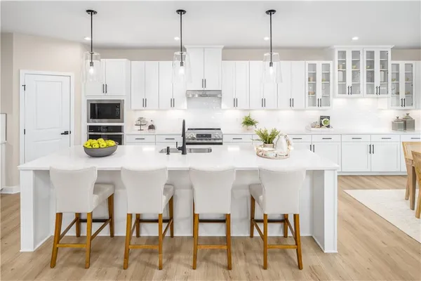 a kitchen with stainless steel appliances kitchen island granite countertop a table chairs and a refrigerator