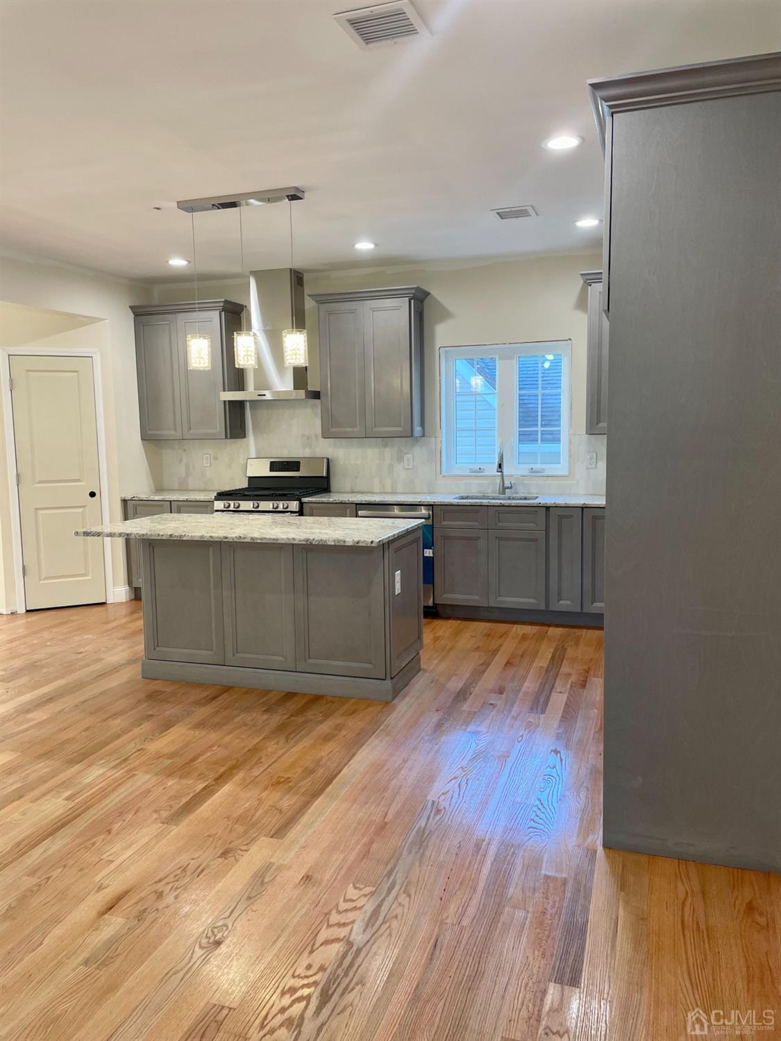125 Ridge Road Colonia, NJ 07067 - Photo 7 of 26 a large kitchen with stainless steel appliances a large counter top and a wooden floors
