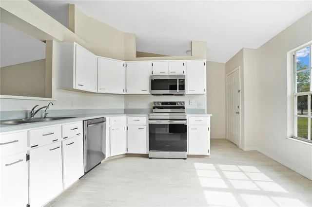 a kitchen with granite countertop a sink cabinets and stainless steel appliances