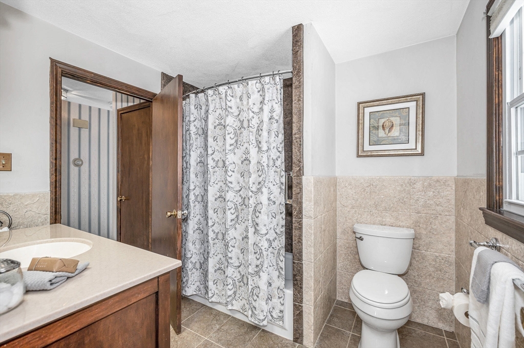 24 Benton Circle Reading, MA 01867 - Photo 20 of 41 a bathroom with a granite countertop toilet a sink and a mirror