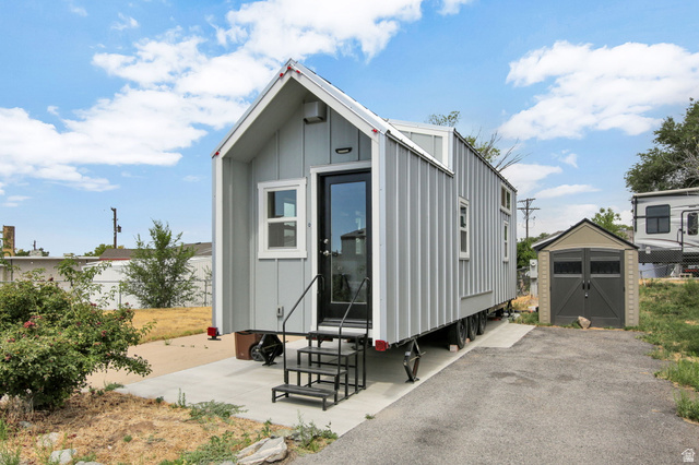 Tiny home featuring vertical panel siding, multiple windows, and a black-framed glass entry door