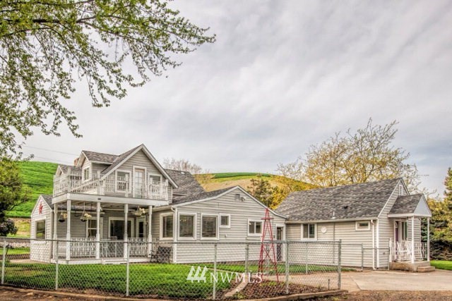 9590 Smith Springs Road Prescott, WA 99348 - Photo 1 of 40 a view of a white house next to a yard with big trees