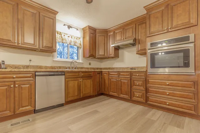 a kitchen with stainless steel appliances granite countertop a stove sink and cabinets