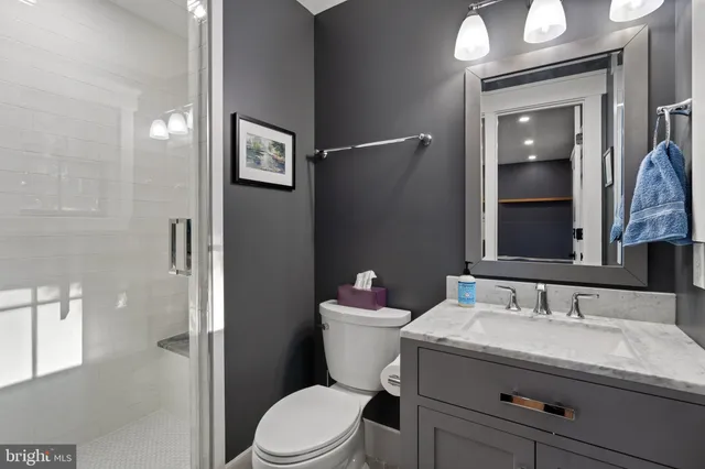 a bathroom with a granite countertop toilet a sink and mirror