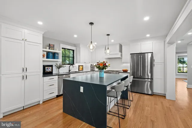 a kitchen with stainless steel appliances granite countertop a refrigerator a sink dishwasher a stove and white cabinets with wooden floor