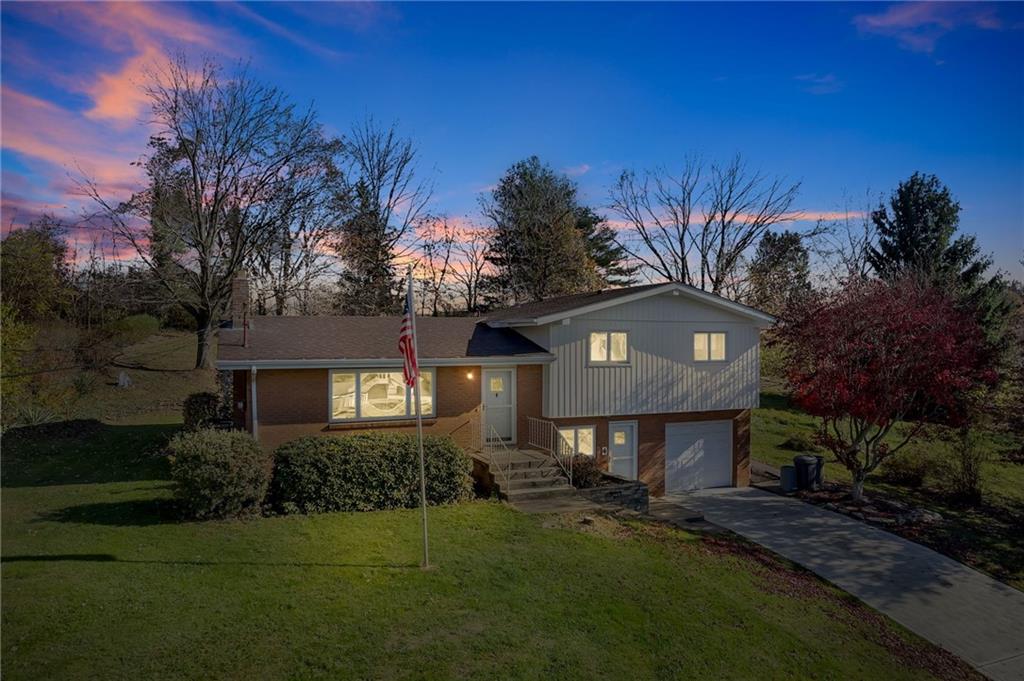 a front view of a house with a yard and tree s