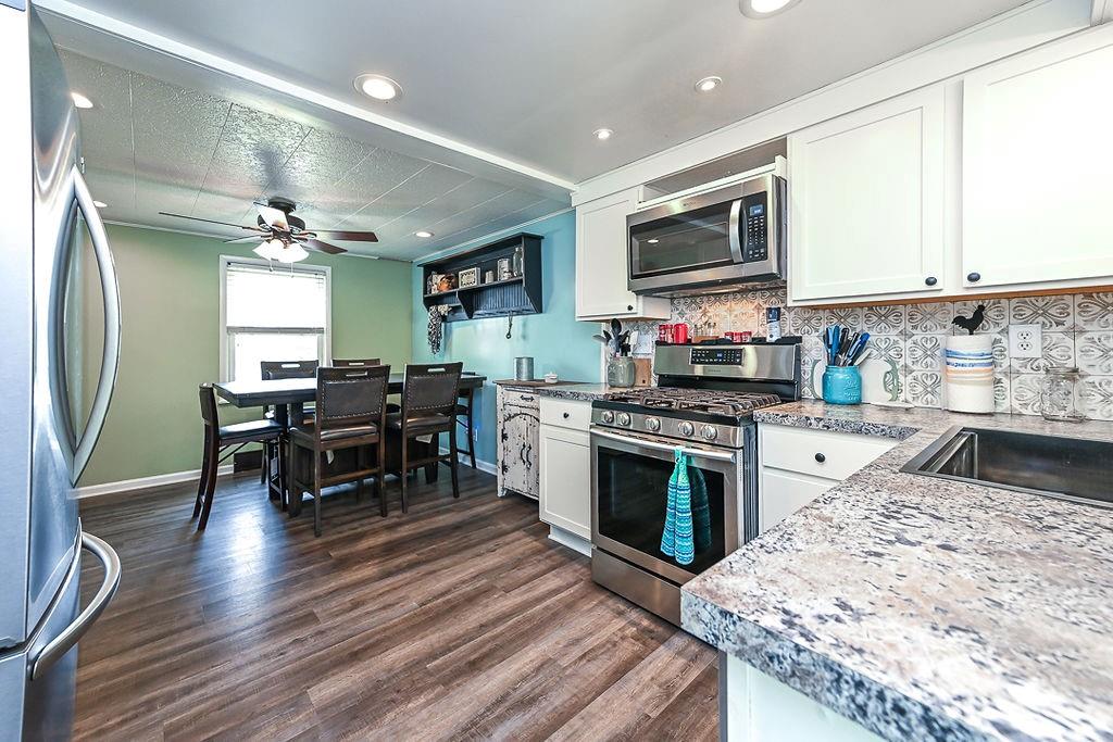 825 Childs Avenue Monaca, PA 15061 - Photo 25 of 35 a kitchen with stainless steel appliances granite countertop a stove top oven a sink dishwasher a dining table and chairs with wooden floor