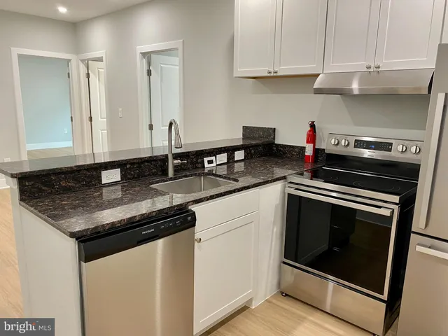 a kitchen with granite countertop white cabinets and stainless steel appliances