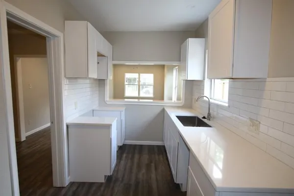 a kitchen with granite countertop white cabinets and sink