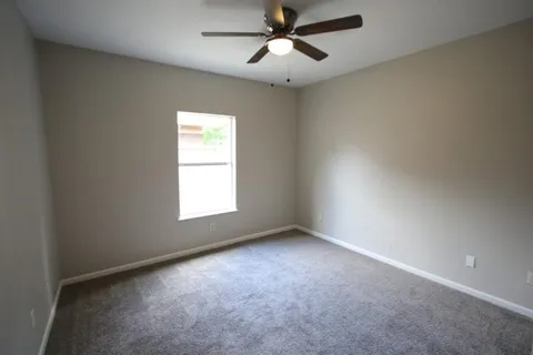an empty room with a ceiling fan and a window