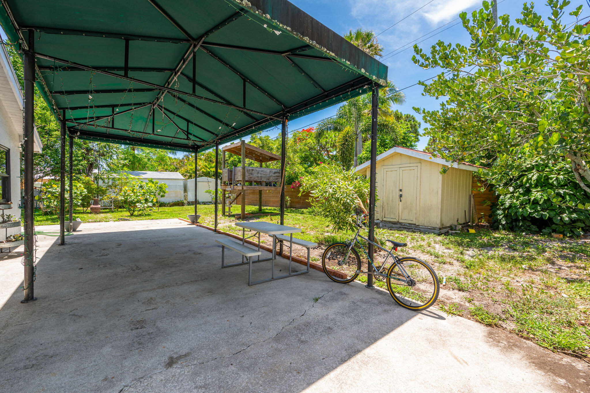 1216 Neoga Street Jupiter, FL 33458 - Photo 19 of 27 a view of backyard with a table and chairs under an umbrella
