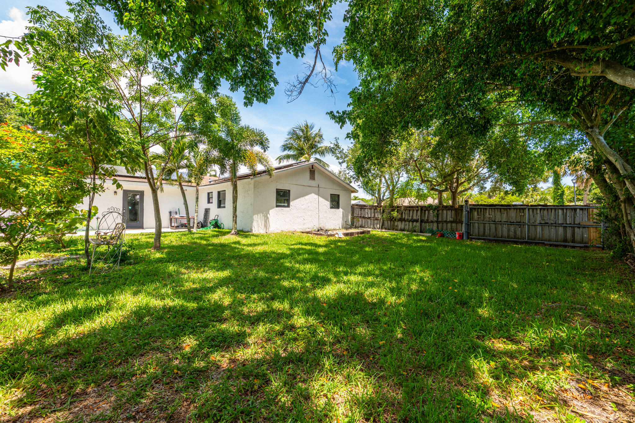 1216 Neoga Street Jupiter, FL 33458 - Photo 21 of 27 a view of a white house with a big yard and large trees