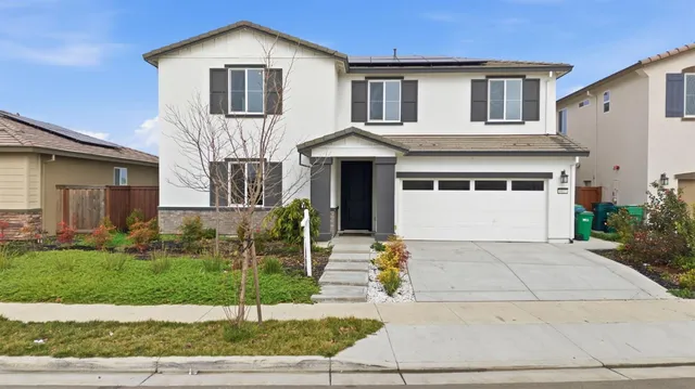 a front view of a house with a garden and garage