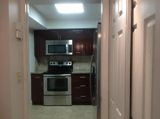 a kitchen with stainless steel appliances granite countertop wooden cabinets and a stove top oven