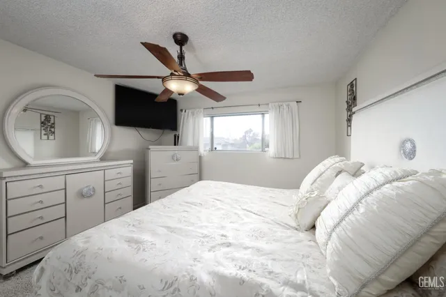 a bedroom with a large bed and a flat tv screen on the dresser