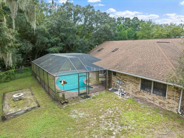 an aerial view of a house with swimming pool and large trees