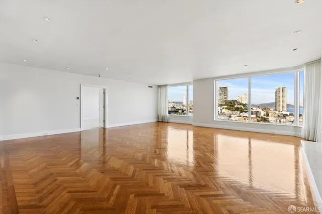 a view of an empty room with window and wooden floor