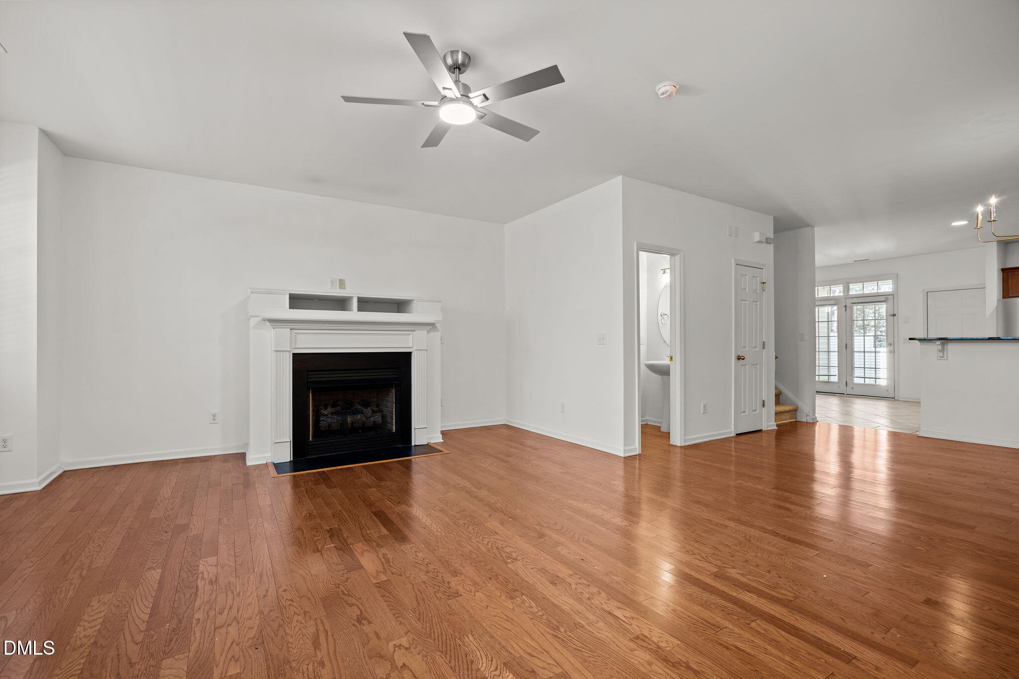 a view of an empty room with a fireplace and a ceiling fan