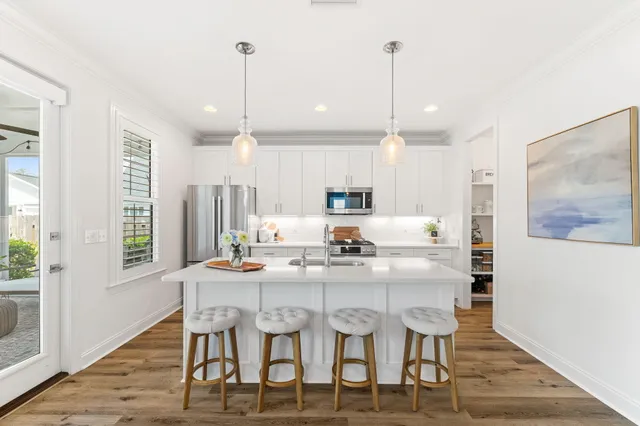 a large white kitchen with a large window a sink and a stove top oven