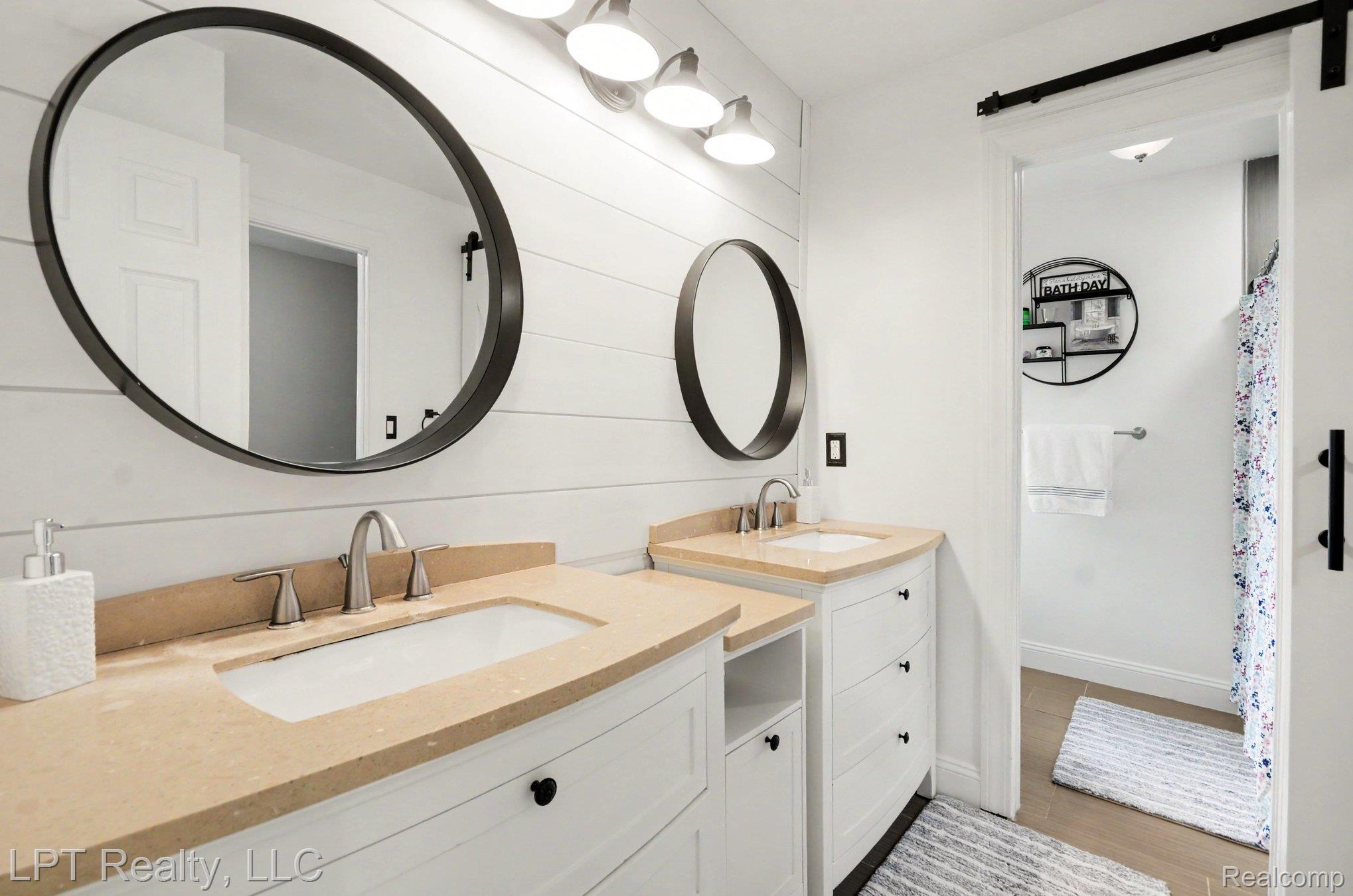 829 Langdon Court Rochester, MI 48307 - Photo 19 of 31 Dual vanity featuring rectangular undermount sinks set in light-toned countertops, contrasting with white cabinetry and matte black hardware
