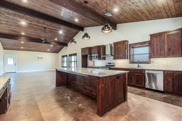 a large kitchen with stainless steel appliances wooden cabinets and a stove
