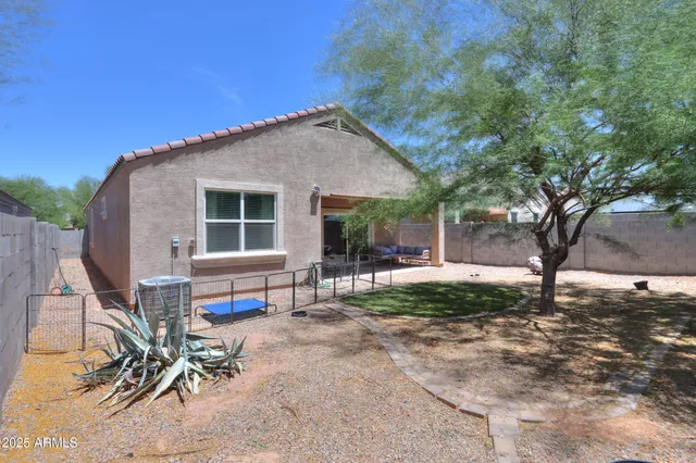 a view of backyard of house with outdoor seating and large trees