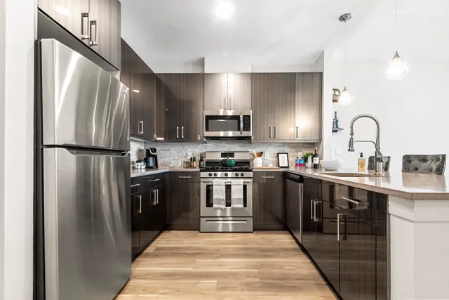 a kitchen with stainless steel appliances granite countertop a refrigerator a stove top oven a sink and dishwasher