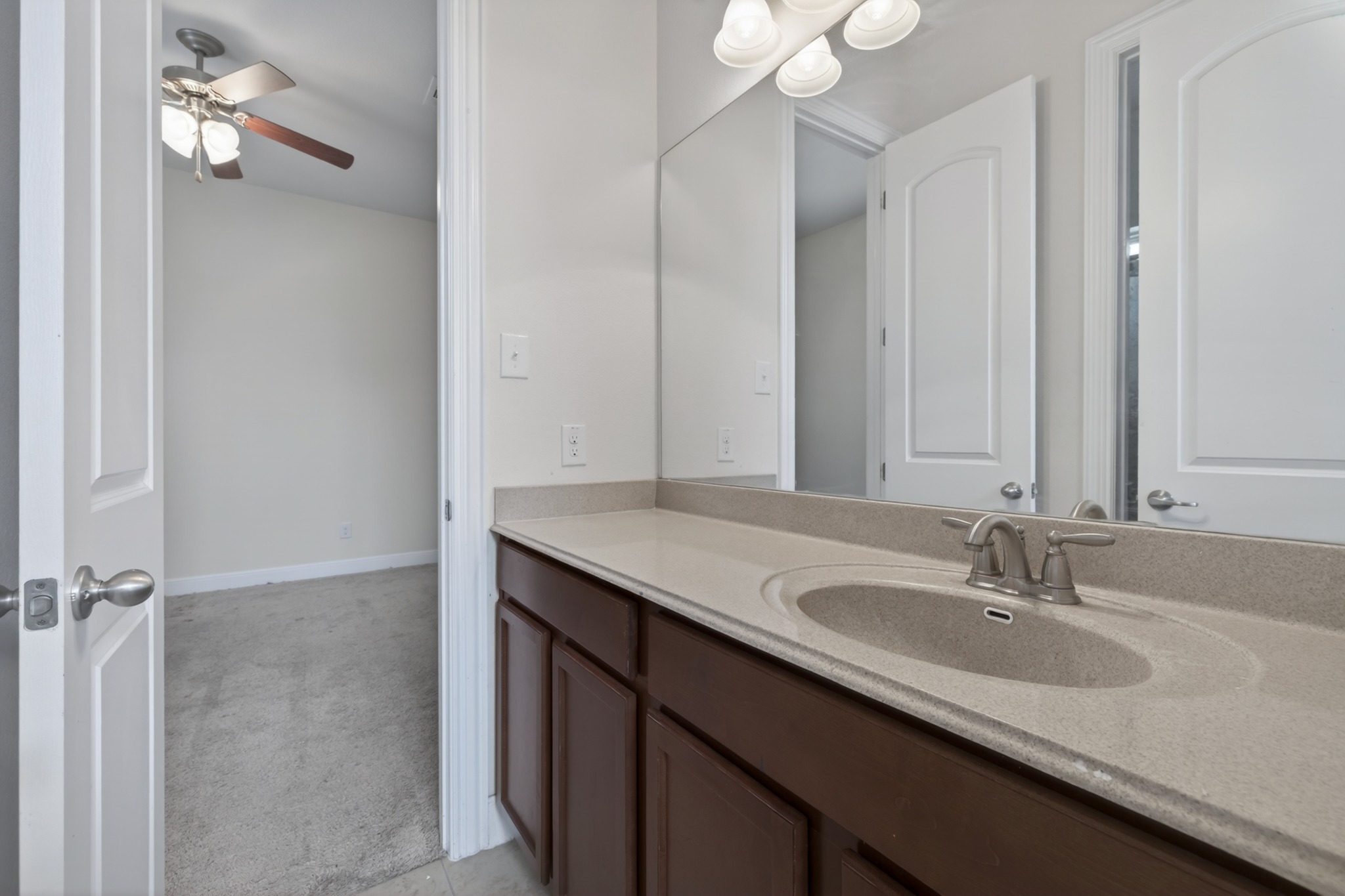 1017 Tabernash Leander, TX 78641 - Photo 27 of 38 Bathroom vanity featuring a single integrated sink with a brushed nickel faucet, a spacious countertop, and dark wood cabinetry