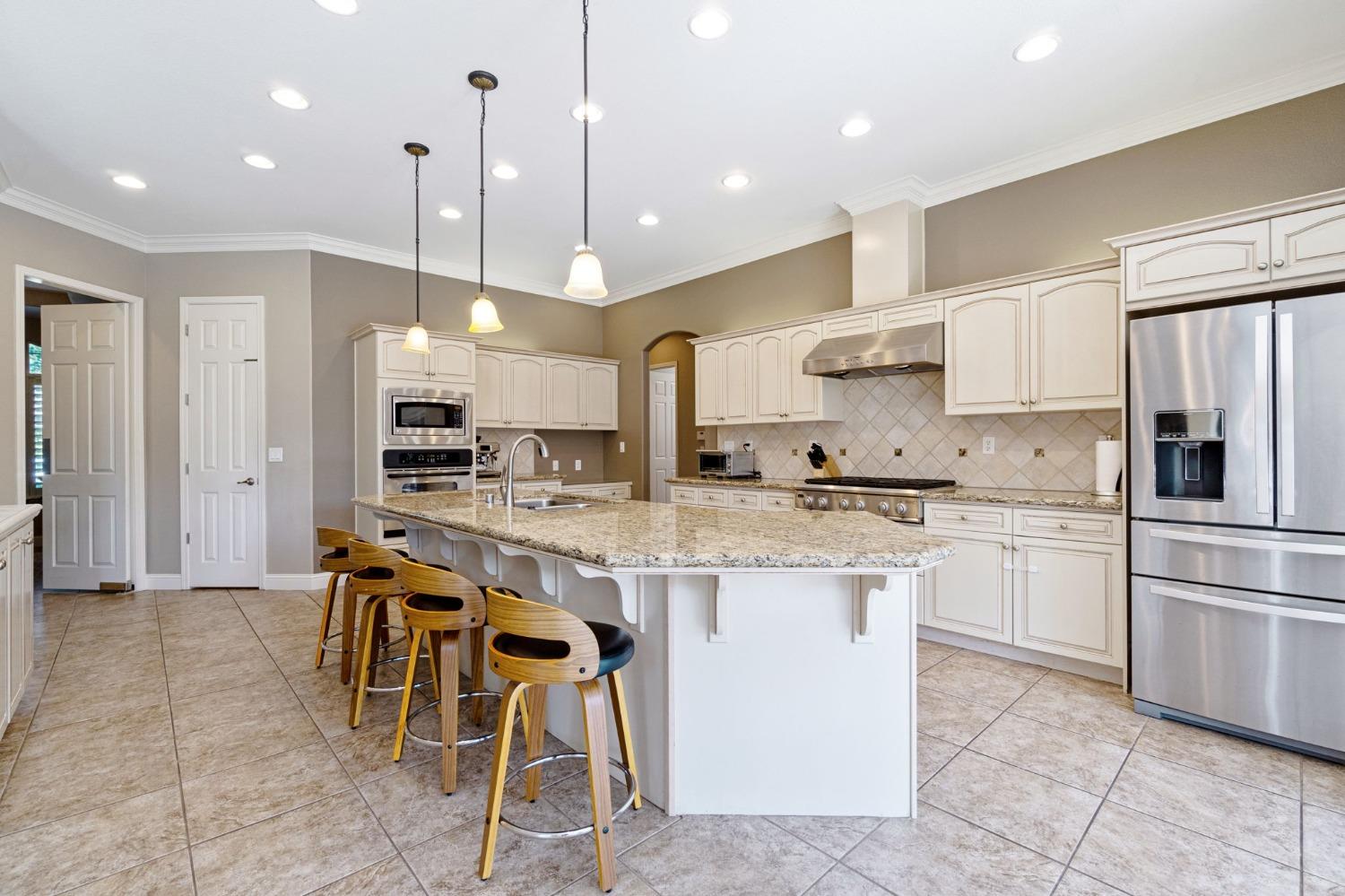 1847 Megan Avenue Clovis, CA 93619 - Photo 15 of 40 a kitchen with stainless steel appliances kitchen island granite countertop a table chairs sink and cabinets