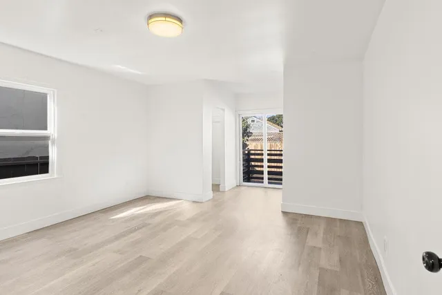 a view of an empty room with a window and wooden floor