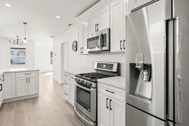 a kitchen with white cabinets and stainless steel appliances